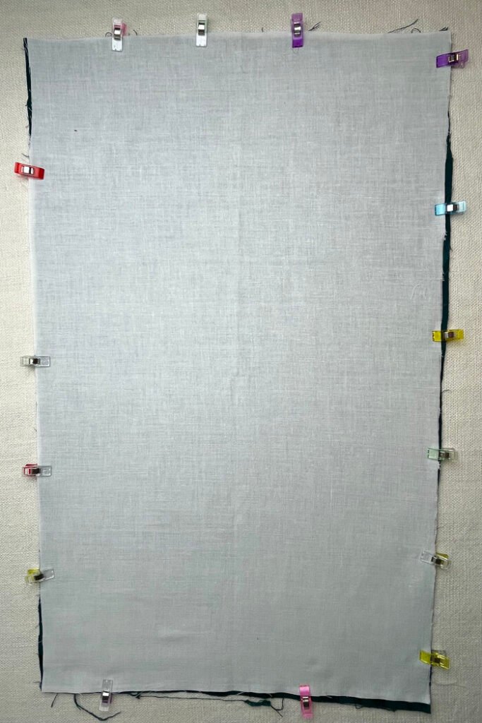 Backing fabric, lining fabric and interfacing layered together and pinned before sewing the advent calendar base panel.