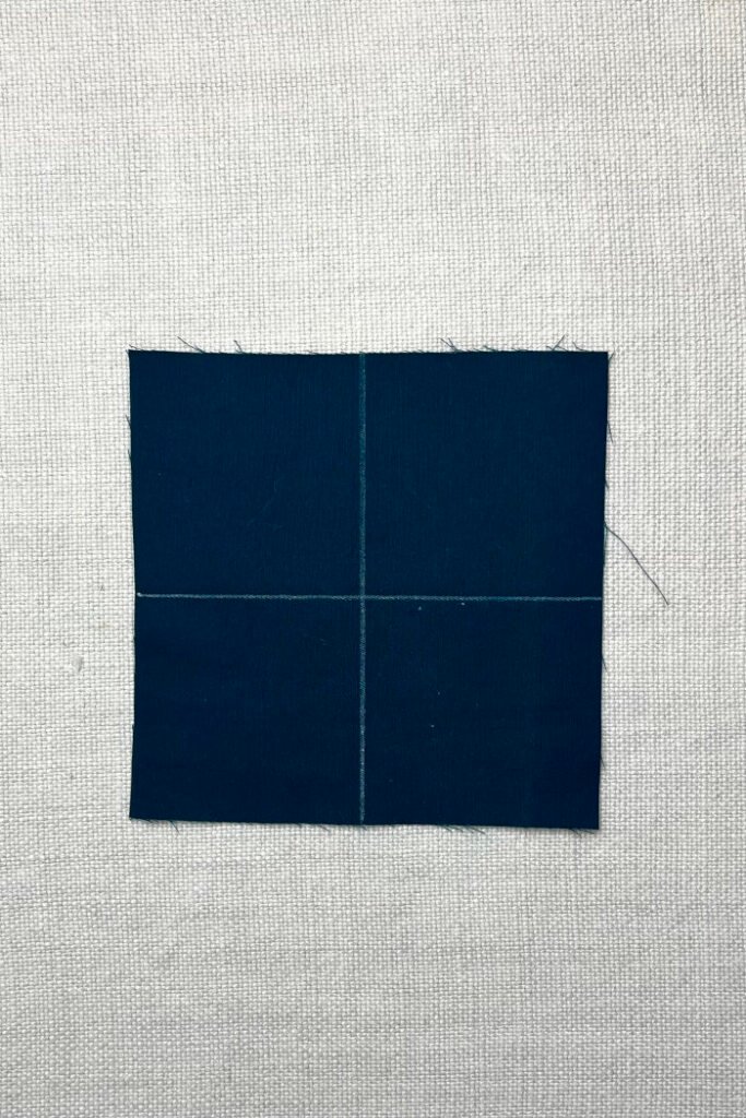 Cut fabric pieces for advent calendar pockets in 3x3 inch squares, ready to stitch and turn.