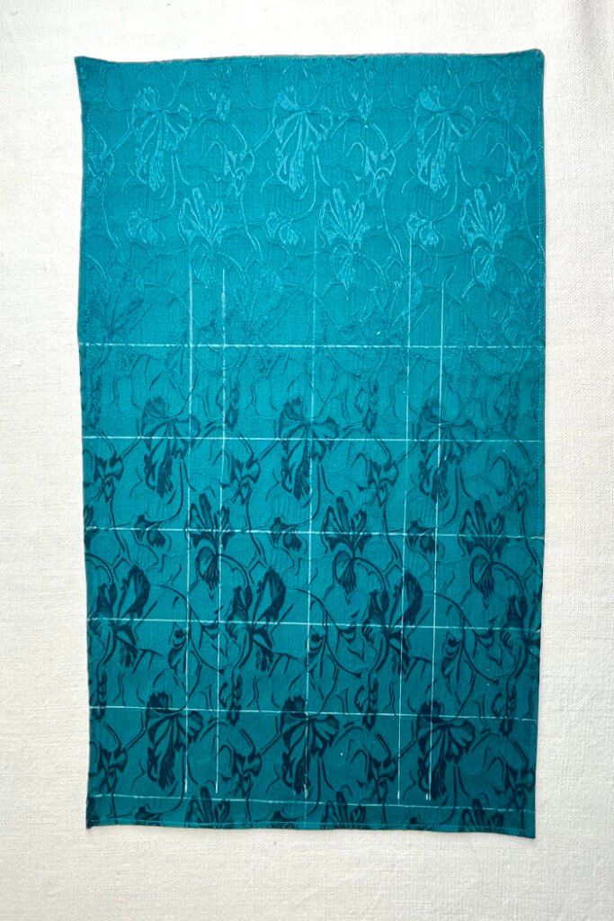 Grid lines drawn on the backing fabric to mark pocket positions for precise placement on the advent calendar.