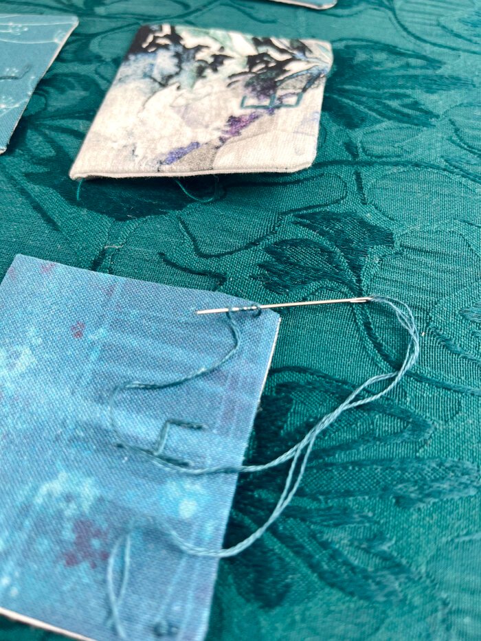 Pressed pockets folded upward with corners tacked in place using decorative embroidery stitches on a handmade advent calendar.