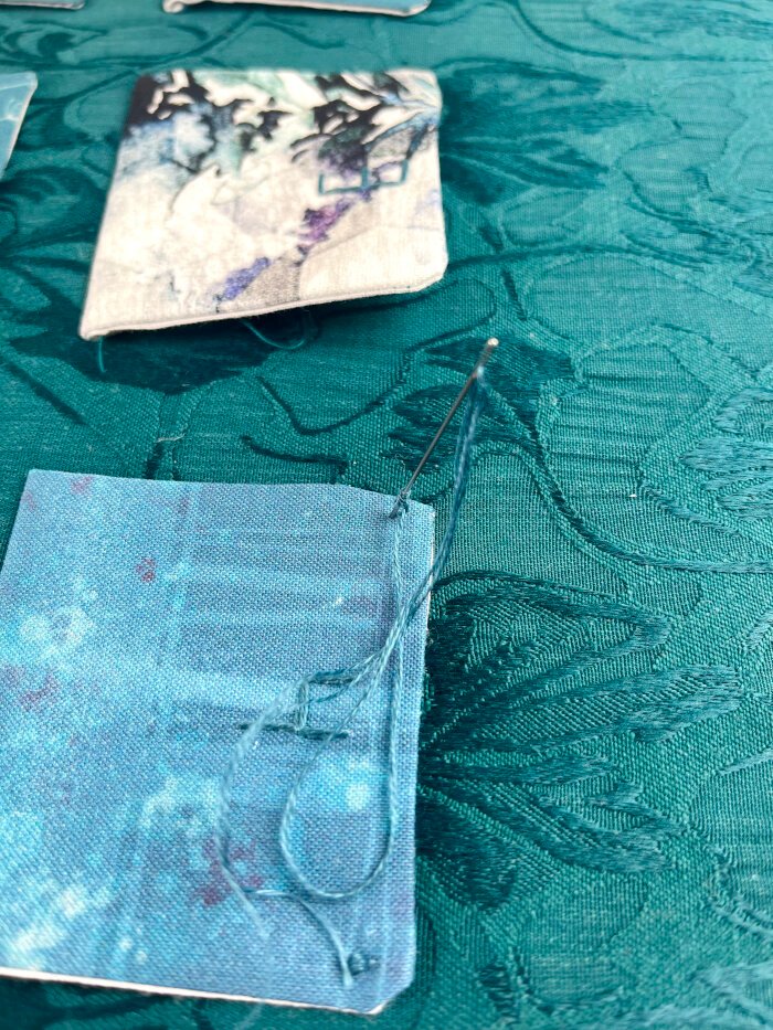 Pressed pockets folded upward with corners tacked in place using decorative embroidery stitches on a handmade advent calendar.