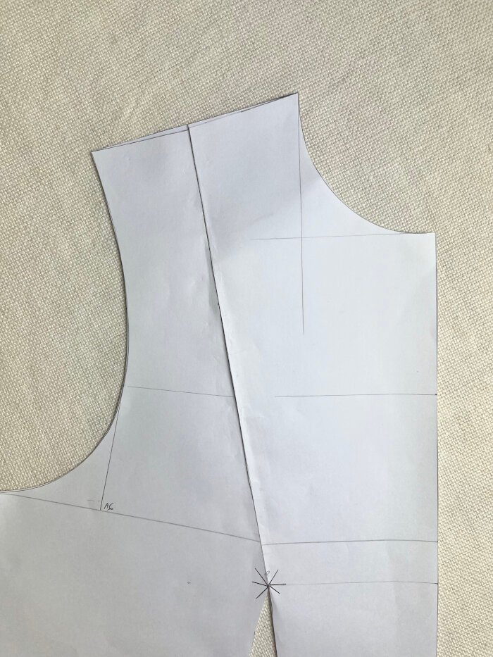 Correcting a dipped shoulder seam on the bodice block by gluing the pattern to paper and redrawing a smooth shoulder line.