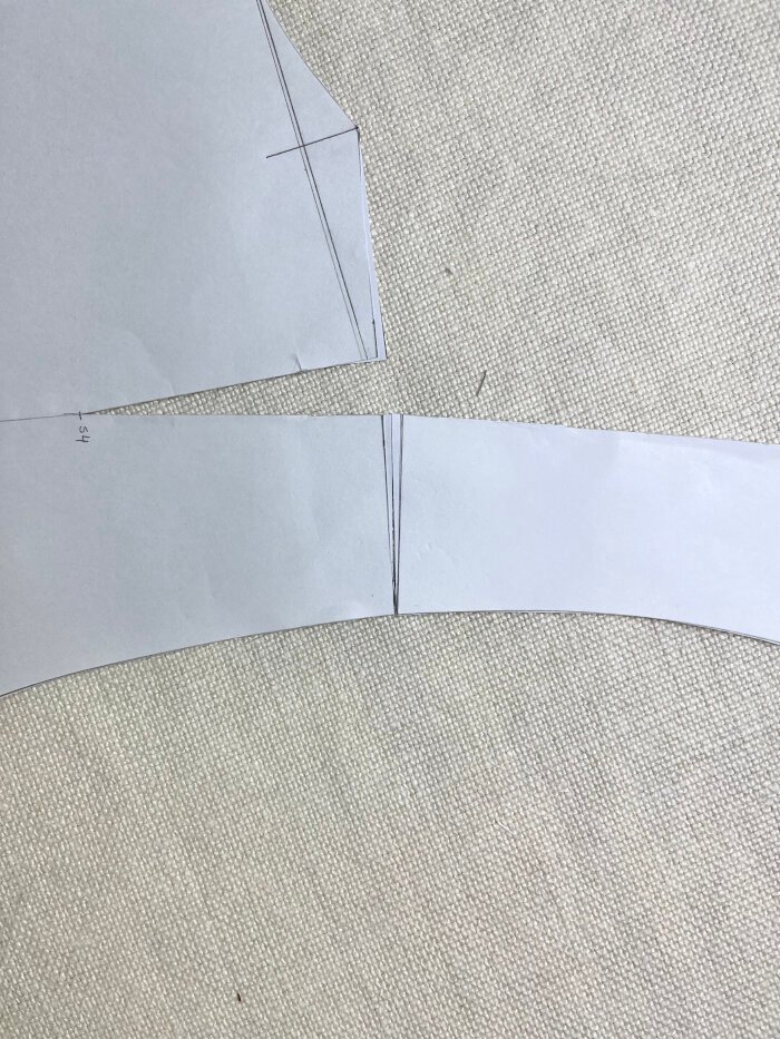 Matching the front and back armhole at the outer shoulder to assess curve continuity and correct sharp angles.