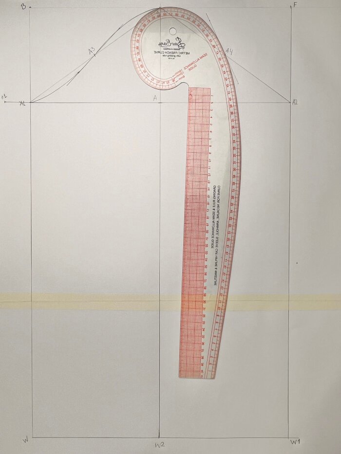 Shaping the front sleeve armhole curve using measured angles and curved rulers.