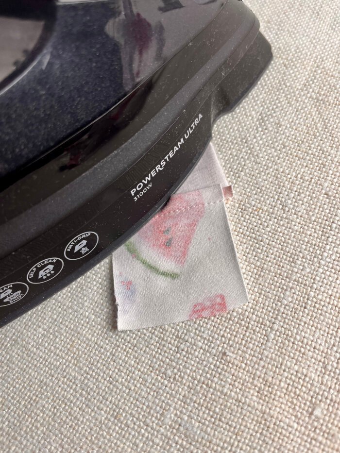 Pressing fabric scrap seams flat after sewing and then pressing the seam allowances to one side for a smooth coaster surface