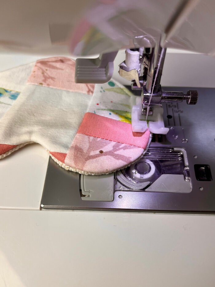 Topstitching around the edge of the heart shaped fabric coaster to secure the layers and close the turning opening