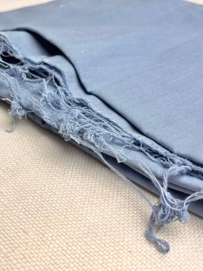 Cotton fabric showing frayed edges due to insufficient edge finish before preshrinking. 