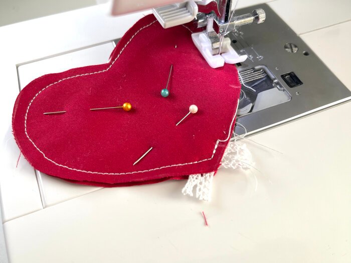 Two heart shaped fabric pieces placed right sides together with lace trim sandwiched inside