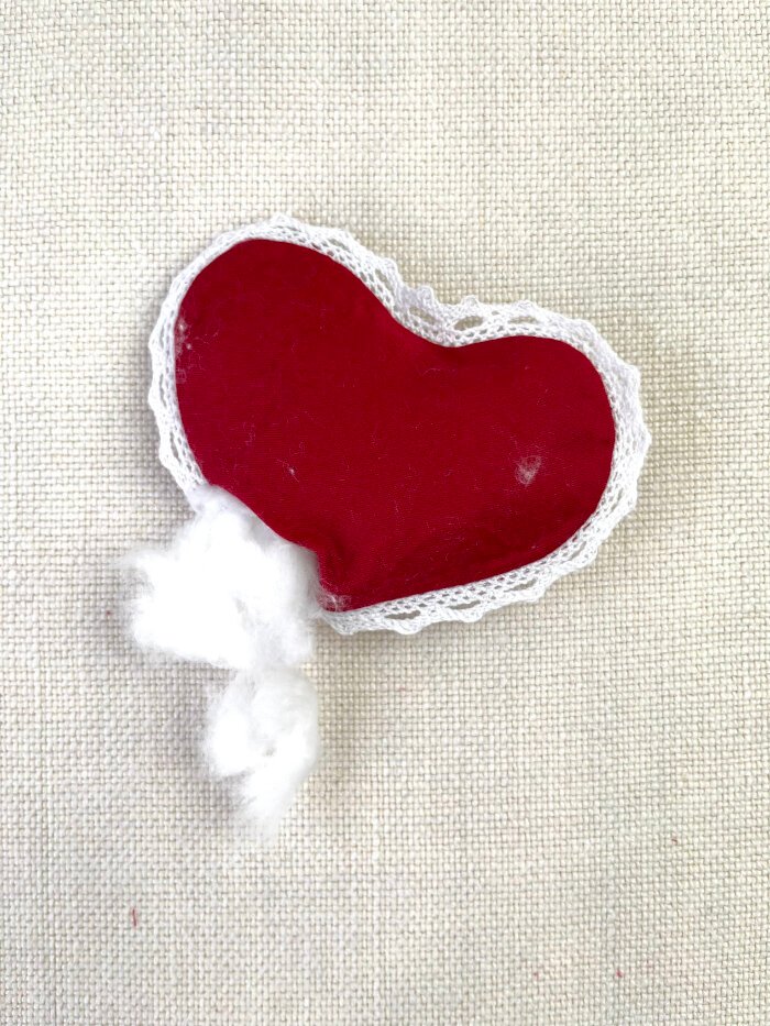 Filling the heart shaped fabric brooch with cotton stuffing for a soft padded shape