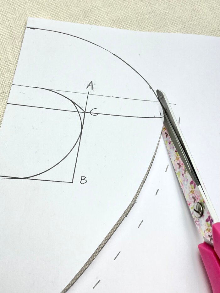 Cutting out drafted baby drool bib pattern from paper for absorbent inner layer