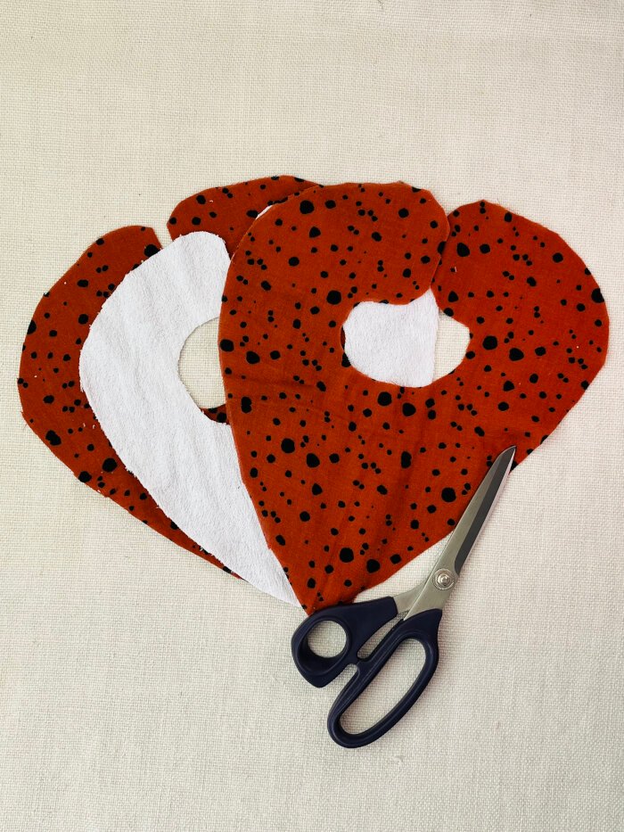 How to Sew a Baby Drool Bib (Easy Step-by-Step Sewing Tutorial) Three fabric layers prepared for sewing a baby drool bib – outer, absorbent, and backing layers