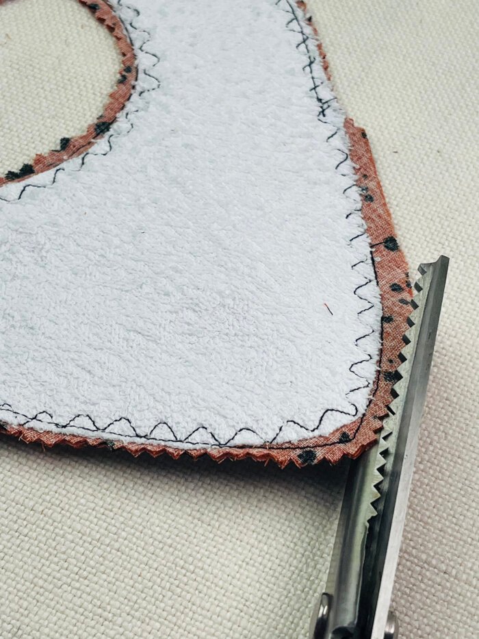 How to Sew a Baby Drool Bib (Easy Step-by-Step Sewing Tutorial) Trimming and clipping seam allowances on a baby drool bib to reduce bulk