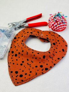 Finished handmade baby drool bib with absorbent fabric layers and snap closure