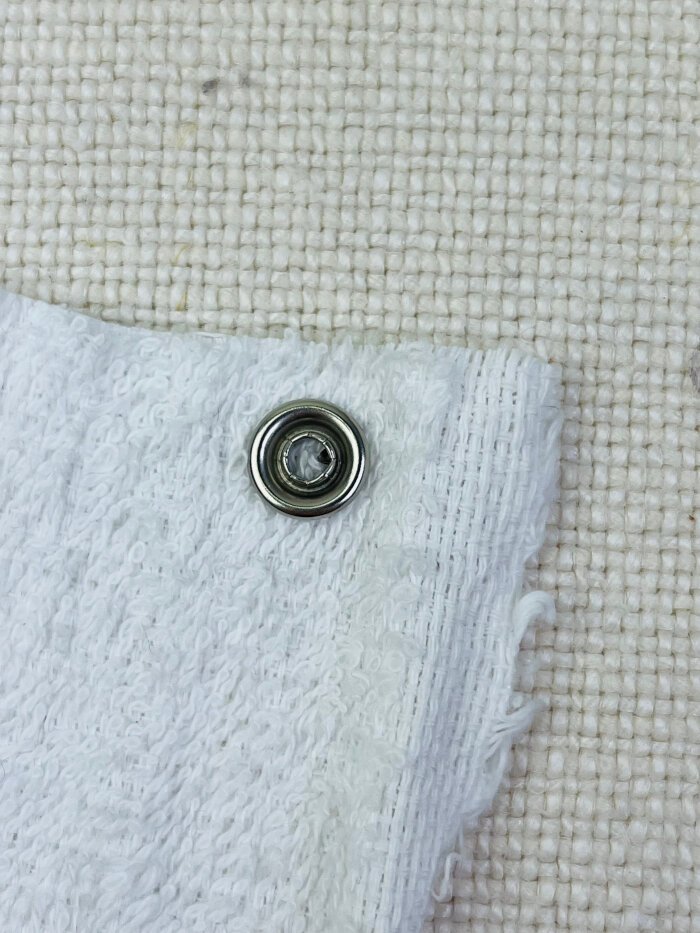 Metal snap button with sharp prong sticking in the centre after applying with hand held pliers 