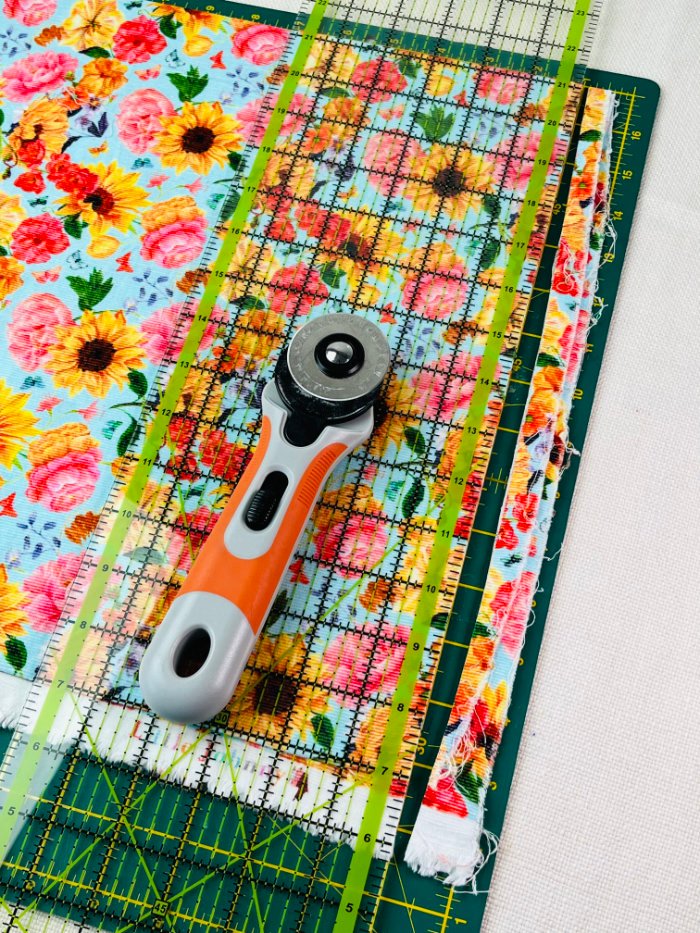 How to Sew a Hair Scrunchie: 4 Easy Methods Using Less Fabric (Beginner-Friendly) Trimming fabric edge on cutting mat to prepare fabric for hair scrunchie tutorial