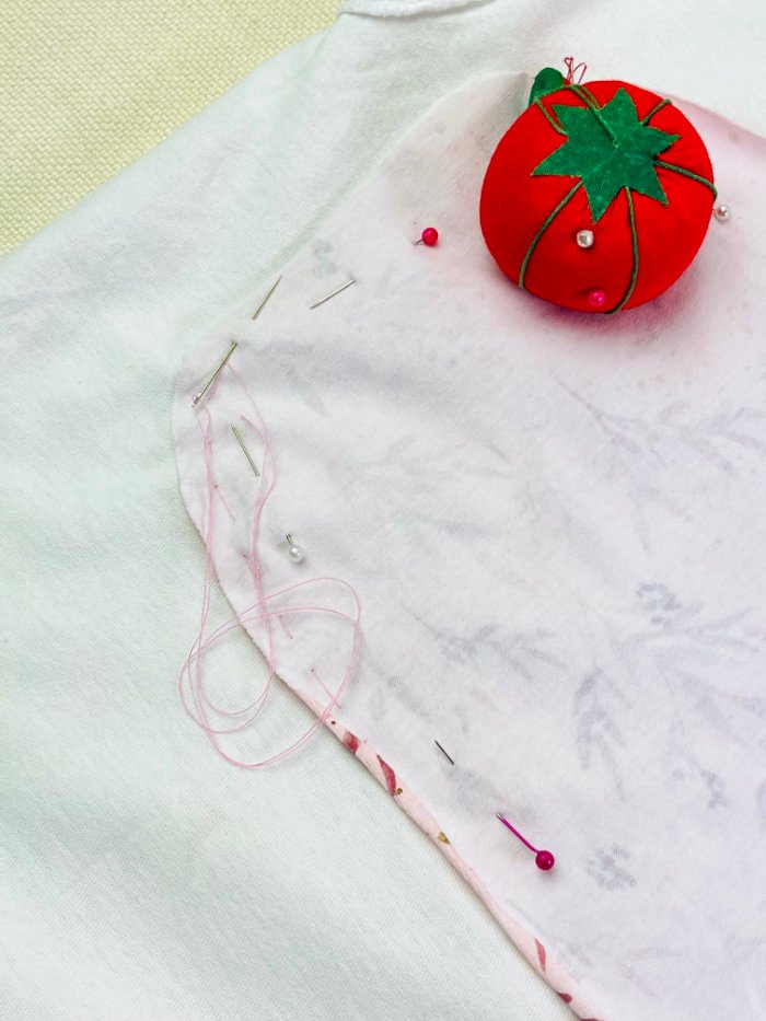 Contrast fabric layered behind T-shirt and hand basted in place for reverse appliqué