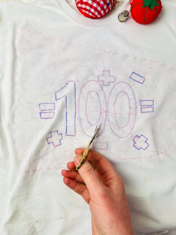 Cutting away the top T-shirt layer to reveal reverse appliqué fabric underneath
