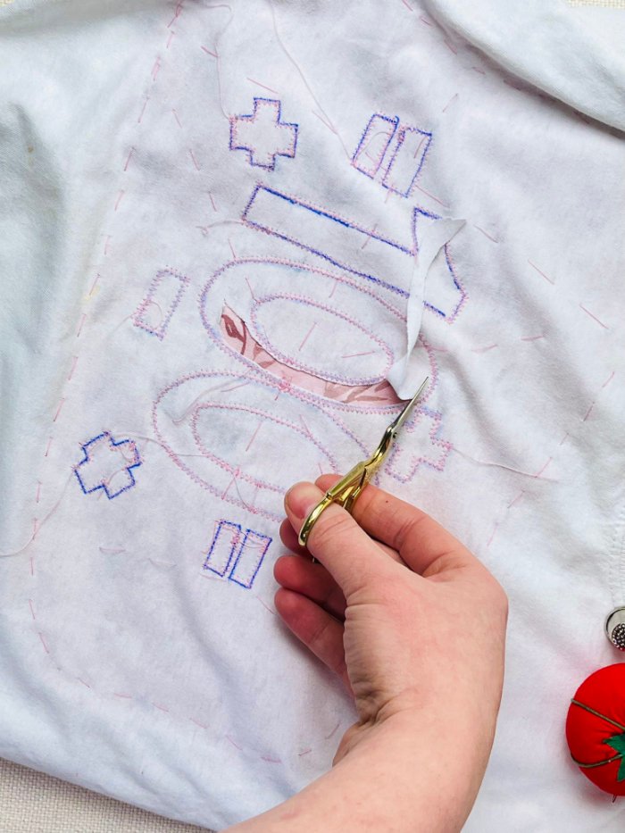 Close-up of trimming fabric close to stitch line for reverse appliqué