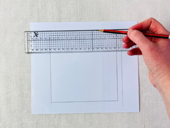 Adding a 1 cm seam allowance to a straight seam on a paper sewing pattern using a grading ruler