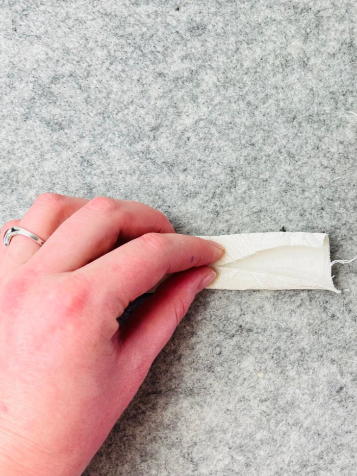 Folding strap edges inward to sew adjustable shoulder strap for laptop bag