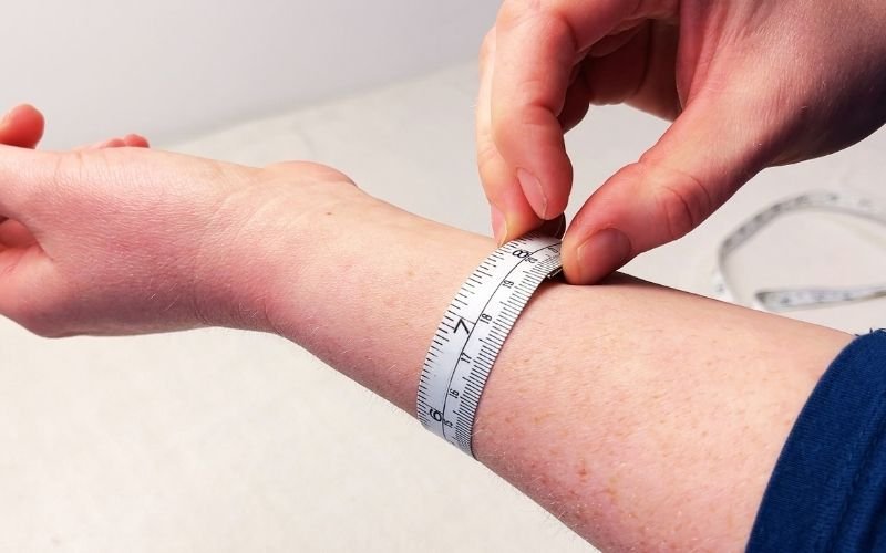 Tape measure wrapped around wrist showing ease allowance for drafting a shirt sleeve cuff pattern