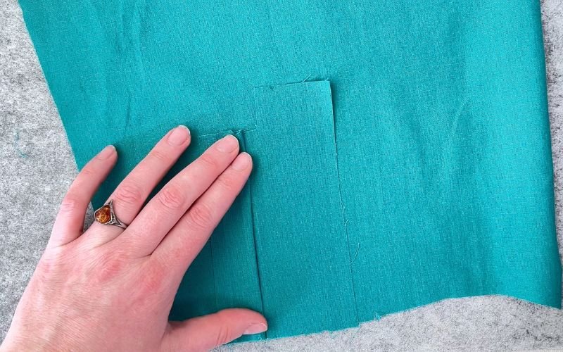 Folding narrows placket side over the sleeve slit