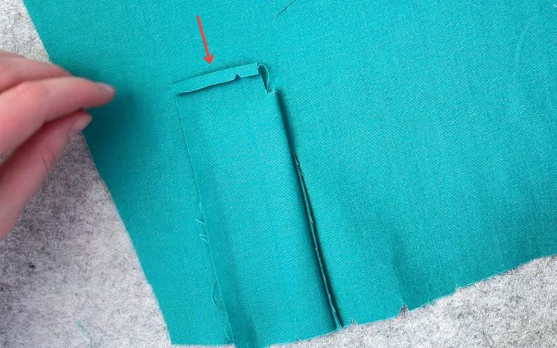 Folding down the upper seam allowance on the upper sleeve placket