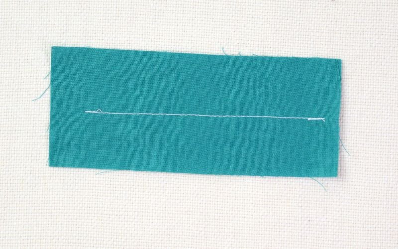 9 Basic Sewing Stitches Every Beginner Must Master Close-up of a straight stitch sample showing even stitching on woven cotton fabric for beginner sewing practice