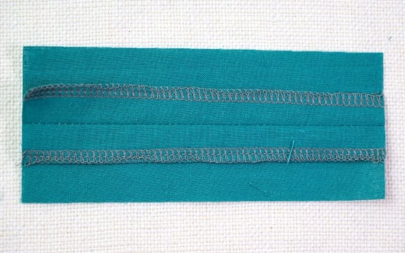 Different Types of Seam Finishes That Look Professional A close-up shot of a classic overlock seam finish (also known as serging) on a woven fabric, showing the neat, professional 4-thread stitch that fully covers the raw edge.