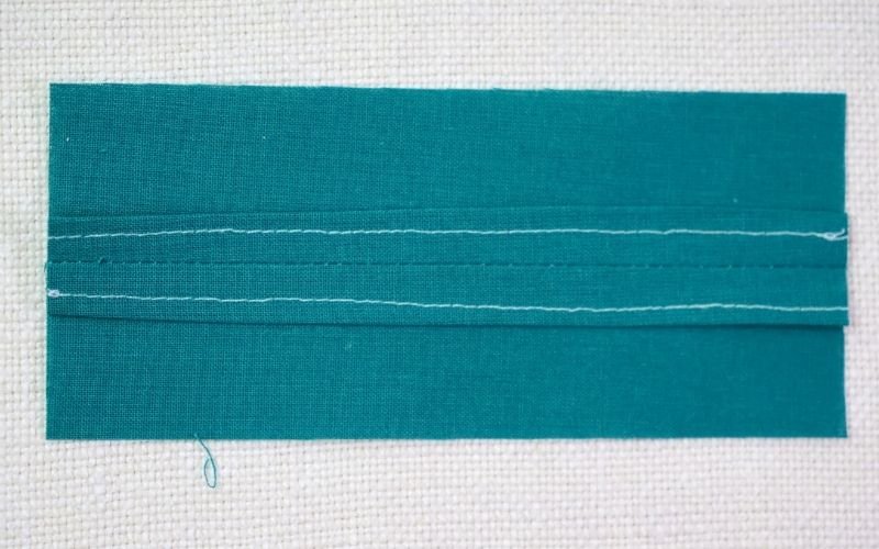 Different Types of Seam Finishes That Look Professional An image of a clean finish edge seam on a fabric sample, showing how the raw edges have been turned under and stitched down, completely hiding them on the wrong side.