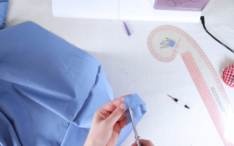 Trimming excess fabric from the button stand near the shirt dress hem